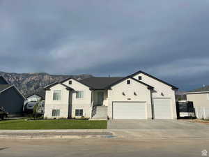View of front of home featuring stucco siding, a front lawn, a garage, and a mountain view