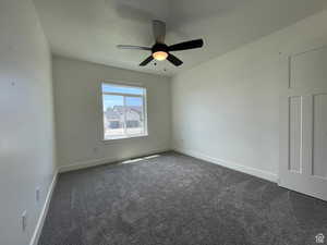 Unfurnished room featuring dark carpet and ceiling fan