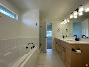 Full bath featuring double vanity, a bath, and light tile patterned floors