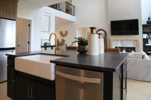Kitchen with an island with sink, open floor plan, stainless steel appliances, and dark cabinets