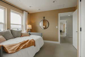 Bedroom with light carpet, arched walkways, and recessed lighting