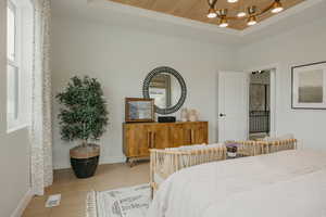 Bedroom with a wooden tray ceiling, light wood-type flooring, and a chandelier