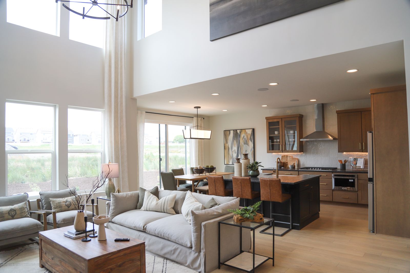 Living area featuring light wood-type flooring, suspended lighting, and a high ceiling