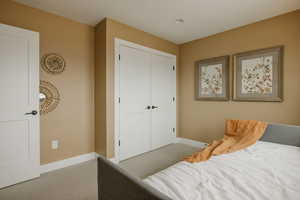 Carpeted bedroom featuring baseboards and a closet