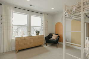 Bedroom with light carpet, arched walkways, and recessed lighting