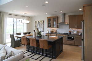 Kitchen featuring a kitchen island with sink, glass insert cabinets, open floor plan, a breakfast bar, and backsplash
