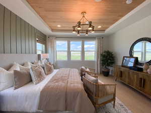 Bedroom featuring a wood tray ceiling, wood finished floors, suspended lighting, and wooden walls