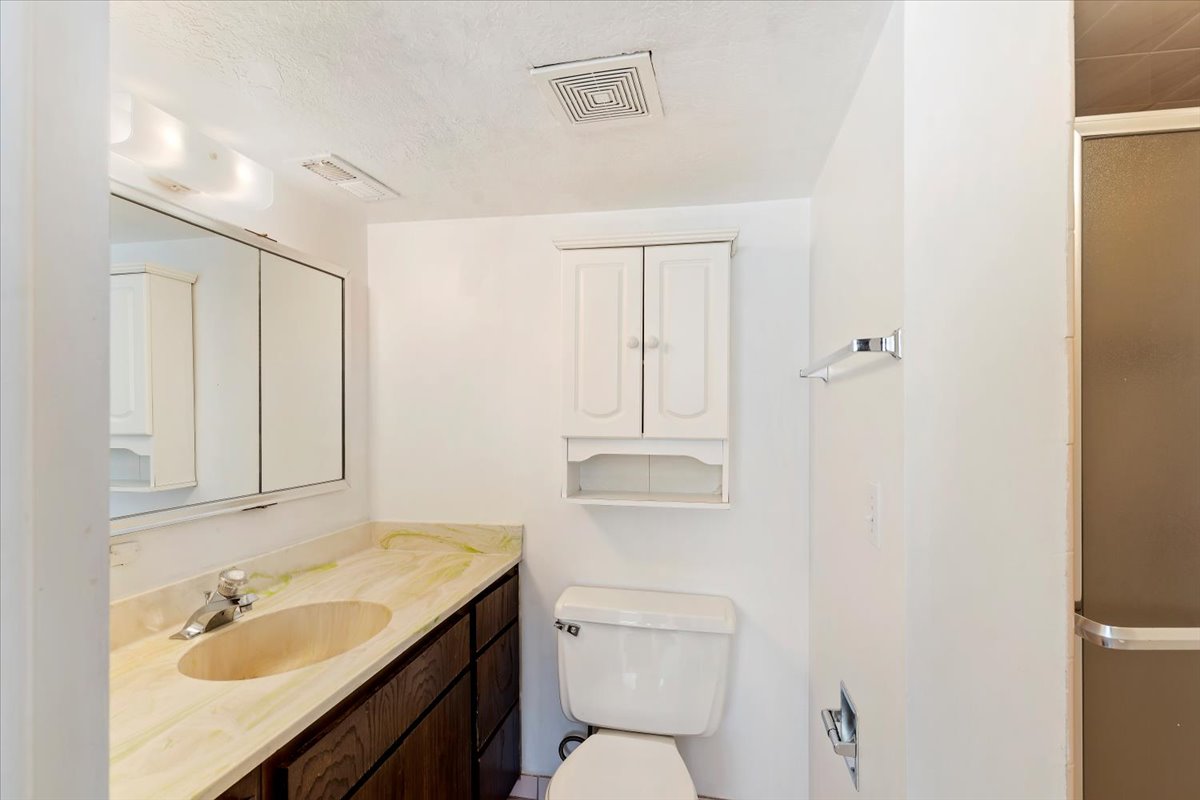 Full bath with a shower stall, vanity, and a textured ceiling
