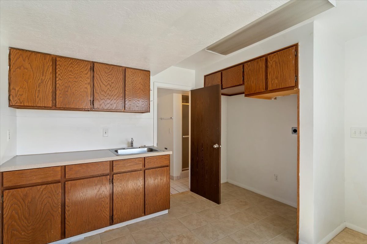 Kitchen with wood finish cabinets, light countertops, a textured ceiling, and light tile patterned floors