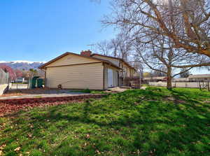 View of side of home featuring a gate, a chimney, and a mountain view
