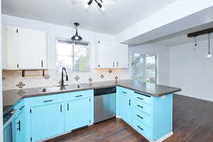 Dual tone kitchen featuring dark countertops, stainless steel appliances, decorative light fixtures, healthy amount of natural light, and dual tone cabinetry