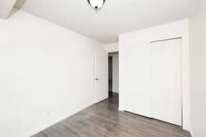 Unfurnished bedroom featuring dark wood-style floors, a textured ceiling, and a closet
