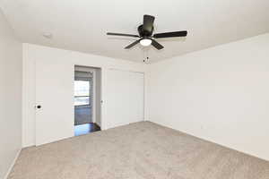 Unfurnished bedroom featuring carpet floors, a textured ceiling, a closet, and ceiling fan