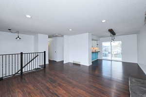 Empty room featuring dark wood-style floors, a textured ceiling, and recessed lighting