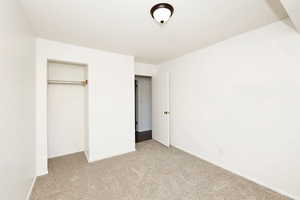 Unfurnished bedroom with light carpet, a closet, and a textured ceiling
