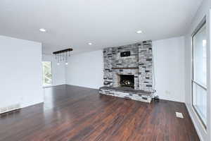 Unfurnished living room with a textured ceiling, a fireplace, dark wood finished floors, and recessed lighting