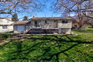 Rear view of house featuring a lawn, a wooden deck, a chimney, and a patio