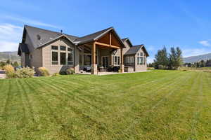 Rear view of property featuring a mountain view, a patio area, outdoor seating, a lawn, and a presidential shingled roof