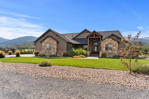 Craftsman-style home featuring a mountain view, stone siding, and a front yard