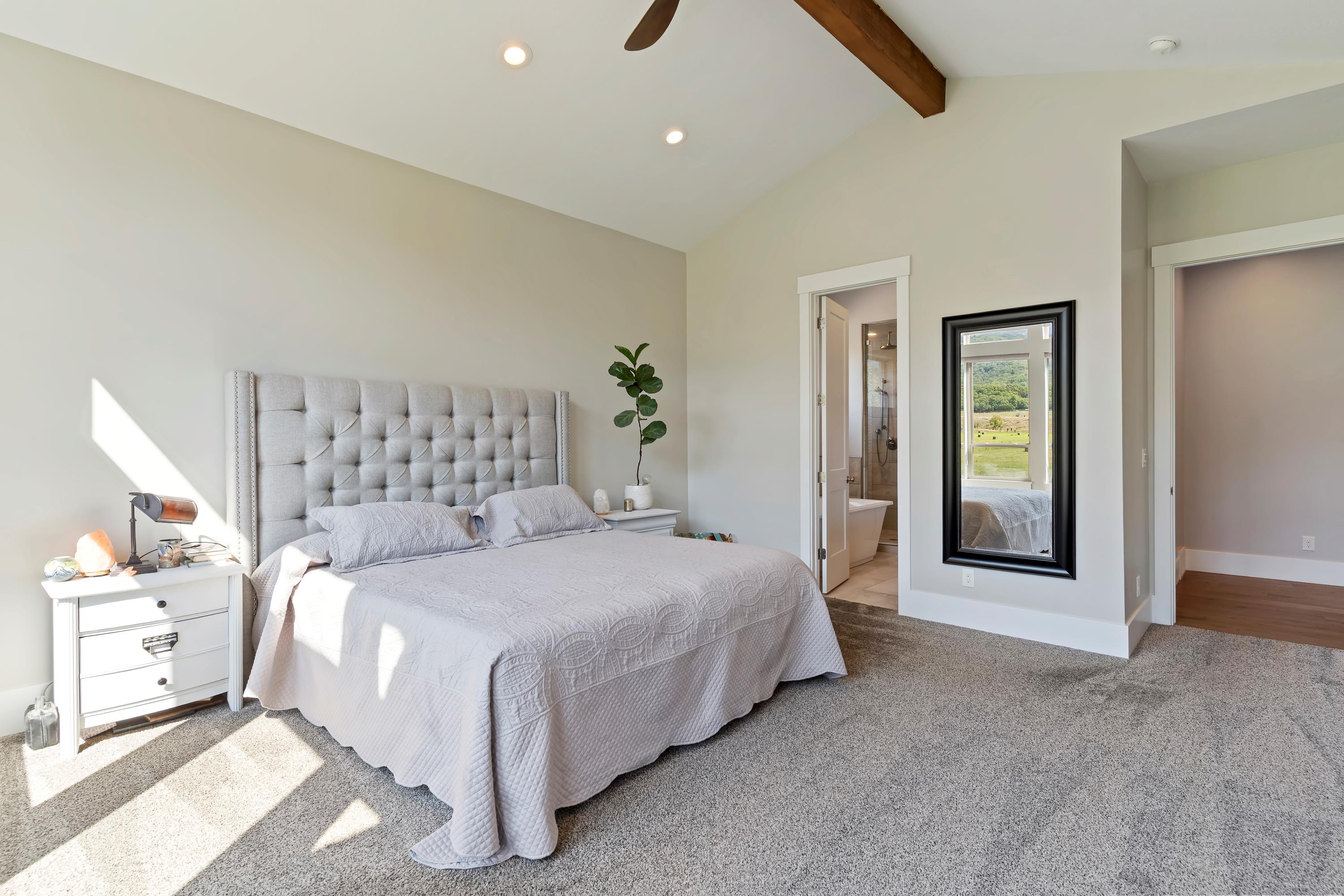 Primary Bedroom featuring light carpet, beam ceiling, recessed lighting, ensuite bathroom, and a ceiling fan