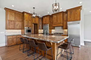 Kitchen with gas range, custom walnut wood cabinets, granite and large island.