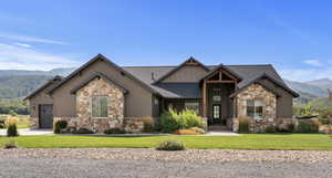 Craftsman inspired home with a mountain view, stone siding, custom timber beams.