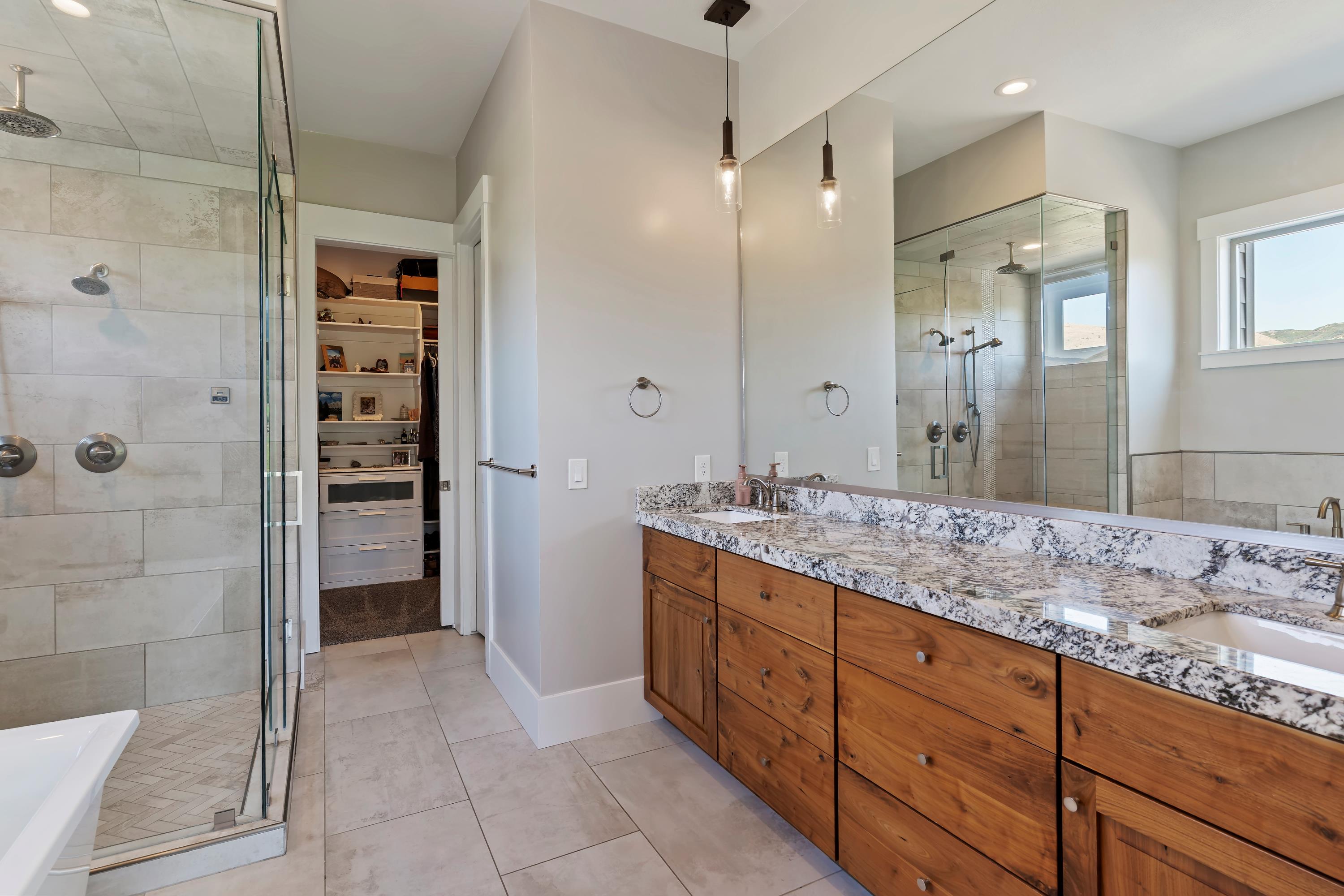 Full bathroom featuring a stall shower, double vanity, a soaking tub, a walk in closet, and light tile patterned flooring