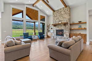 Living area featuring light wood finished floors, a stone fireplace, a mountain view, and lofted ceiling