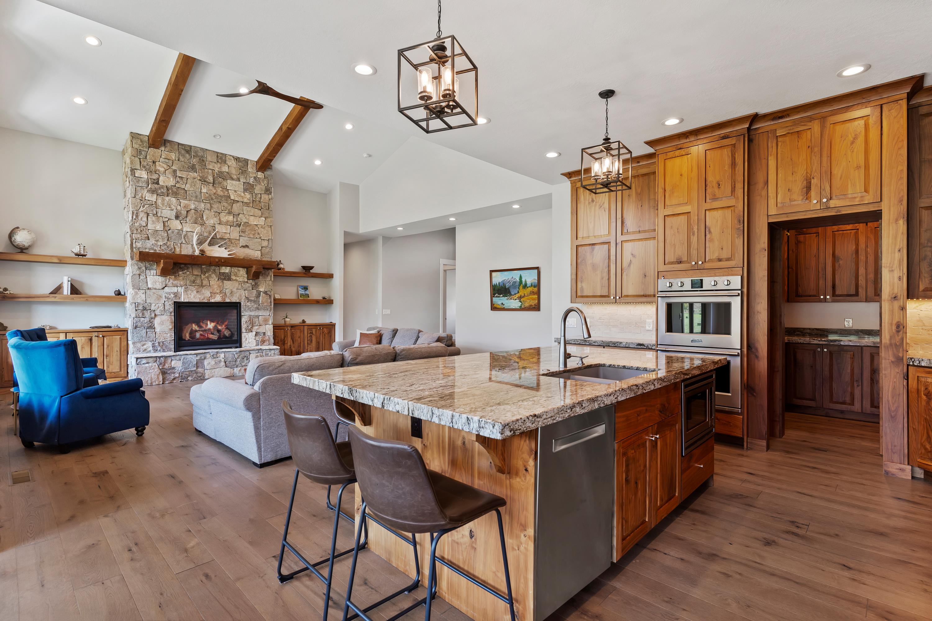 Kitchen with gas range, custom walnut wood cabinets, granite and large island. Opening to living room.
