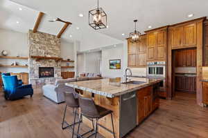 Kitchen with gas range, custom walnut wood cabinets, granite and large island. Opening to living room.