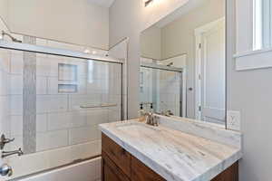 Full bath featuring vanity and shower / bath combination with glass door