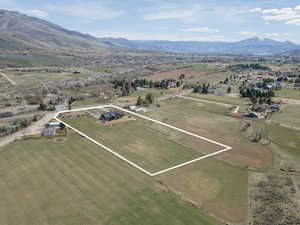 Aerial view of property and surrounding area with mountains, property parcel outlined, and rural landscape
