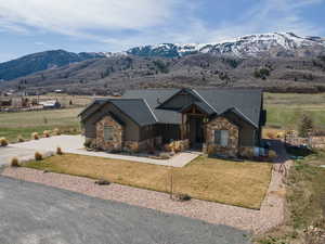 Craftsman inspired home with stone siding, a front lawn, and a mountain view