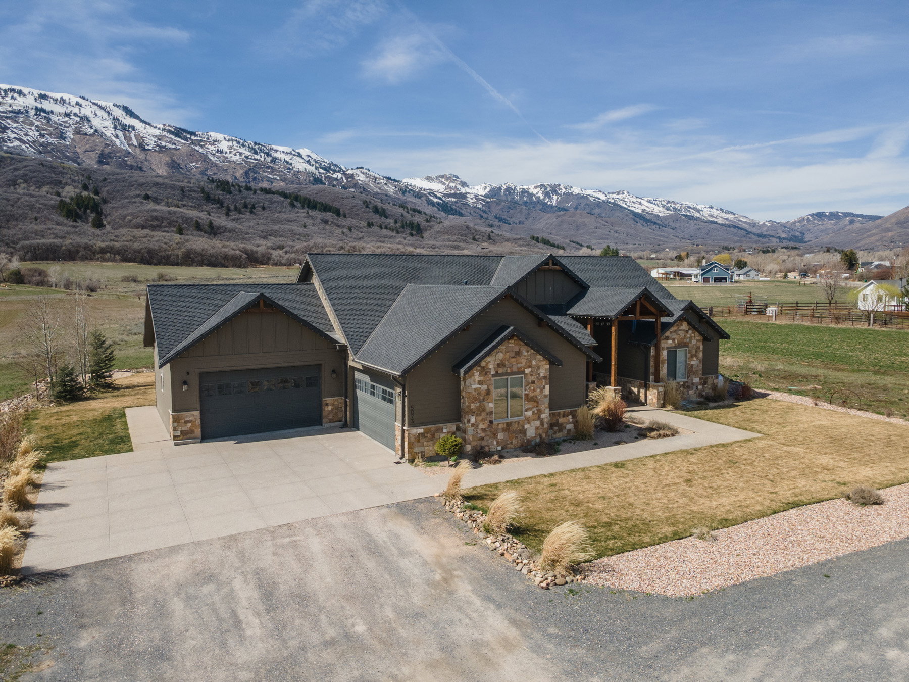 Craftsman house with stone siding, a garage, driveway, and a front lawn