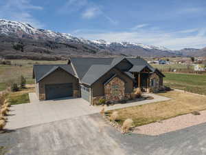 Craftsman house with stone siding, a garage, driveway, and a front lawn