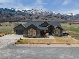 Craftsman-style home with stone siding, a front lawn, driveway, and a mountain view