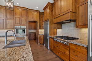 Kitchen with gas range, custom walnut wood cabinets, granite and large island.