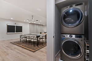 Laundry area featuring stacked washer / dryer, light wood-style floors, and suspended lighting