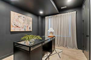 Home office with light wood-style floors and recessed lighting