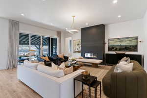 Living area featuring a large fireplace, light wood-type flooring, and recessed lighting