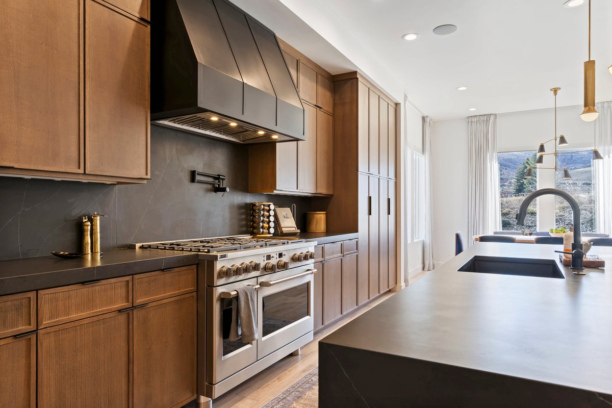 Kitchen featuring range with two ovens, hanging light fixtures, decorative backsplash, light wood-type flooring, and wood finish cabinets