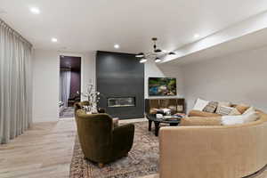 Living area featuring light wood finished floors, a large fireplace, and recessed lighting