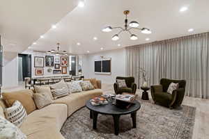 Living area with wood finished floors, ceiling fan, and hanging lights