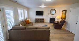 Living room with light wood-type flooring, a tile fireplace, and a textured ceiling