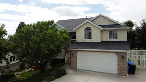 Traditional-style home with roof with shingles, concrete driveway, a garage, and brick siding