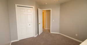 Unfurnished bedroom with dark colored carpet and a closet