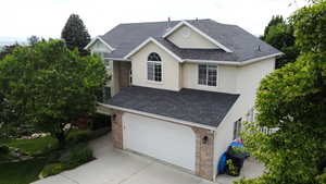Traditional home featuring brick siding, driveway, roof with shingles, an attached garage, and stucco siding