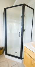 Full bath featuring vanity, a shower stall, and light tile patterned flooring