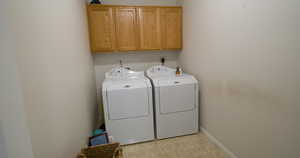 Laundry area with light flooring, washer and clothes dryer, and cabinet space