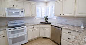 Kitchen with white appliances, light stone counters, white cabinets, and light wood-style floors